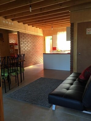 A cozy living area with a sofa, a dining table with chairs, and a kitchen in the background.