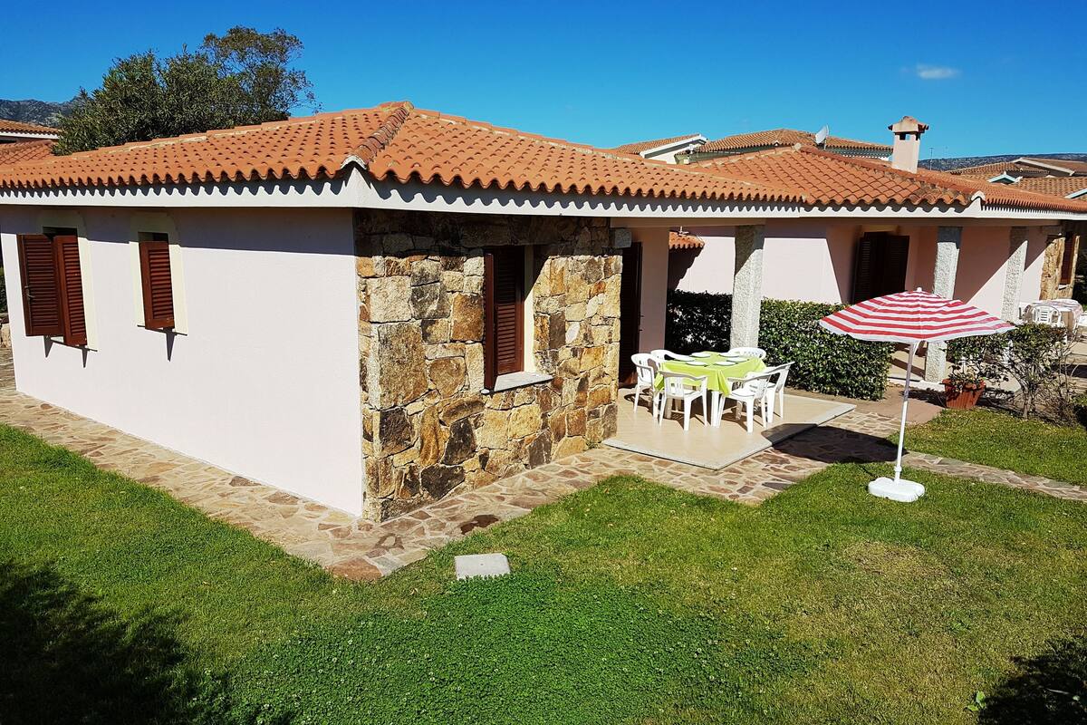 Uma casa com telhado de telhas, paredes de pedra e um pátio com mesa e cadeiras.