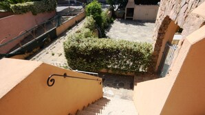 A staircase leading down to a courtyard with a small garden and a stone wall. - Casa Nadia (San Teodoro)