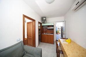 A compact kitchen with wooden cabinets, a built-in sink, and a small television. - La Rotonda Sul Mare (Forio)