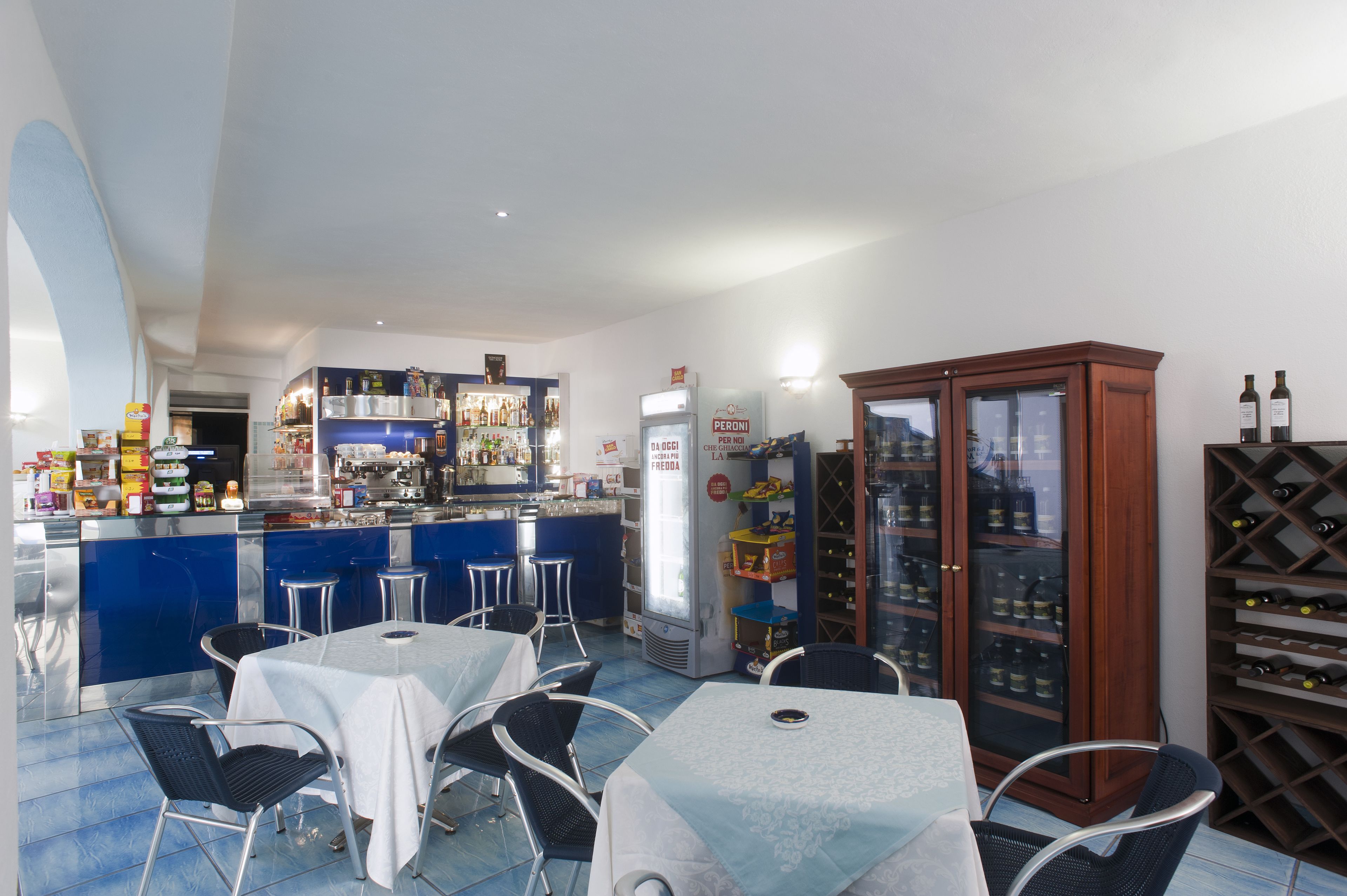 Un restaurante con barra, mesas, sillas, una bodega y un refrigerador.