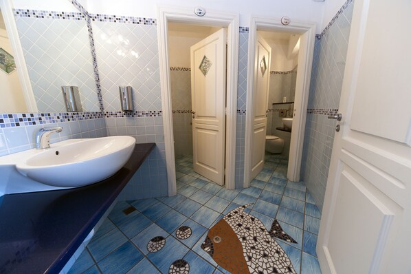 A bathroom with a white sink, blue and white tiled walls, and a fish mosaic on the floor. - La Rotonda Sul Mare (Forio)