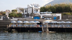 A waterfront property with a dock, umbrellas, and a building with a blue door.
