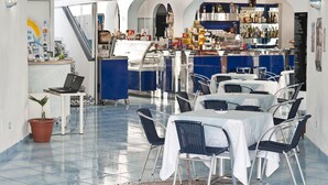 A restaurant with a bar area, tables, chairs, and a laptop on a table.