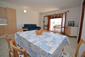 A dining area with a table covered in a blue and white patterned tablecloth, surrounded by wooden chairs.