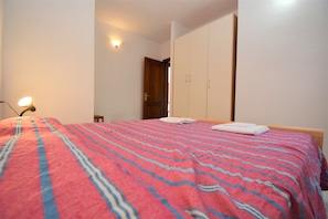 A bedroom with a bed, a nightstand, a lamp, and a wardrobe. - Citai Apartment (San Teodoro)