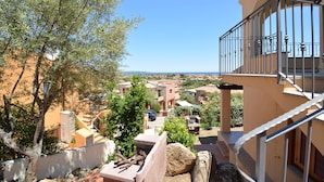 Zona residencial com vista para o mar, apresentando uma varanda com guarda-corpo de metal e estrutura de pedra.