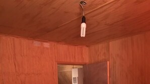 A room with wooden bunk beds, a ceiling light, and a door leading to another room. - Cabaña en Algarrobo 3 El Canelo (Algarrobo)
