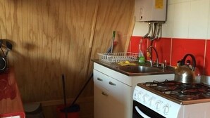 A compact kitchen with a stove, sink, and a small cabinet. - Cabaña en Algarrobo 3 El Canelo (Algarrobo)