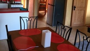 A compact kitchen with a stove, refrigerator, and a dining area with a table and chairs. - Cabaña en Algarrobo 3 El Canelo (Algarrobo)