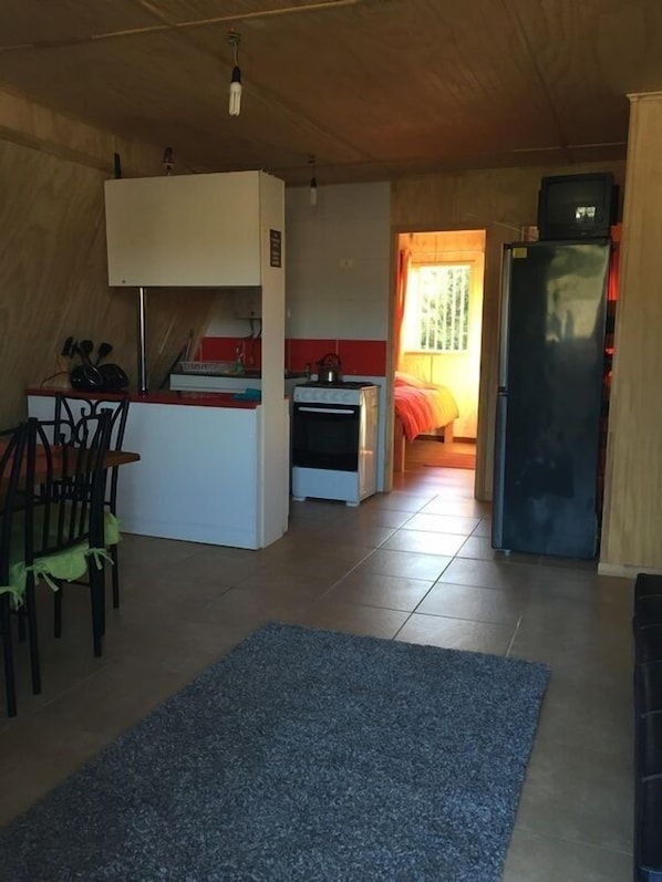 A compact living space with a kitchenette, a dining area, and a bedroom.