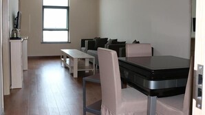 A modern, minimalist living room with a sofa set, a dining table, and a kitchen area with a kettle. - GreenTree Alliance Suzhou Zhangjiagang Huachang Road Bus Station Hotel (Suzhou)