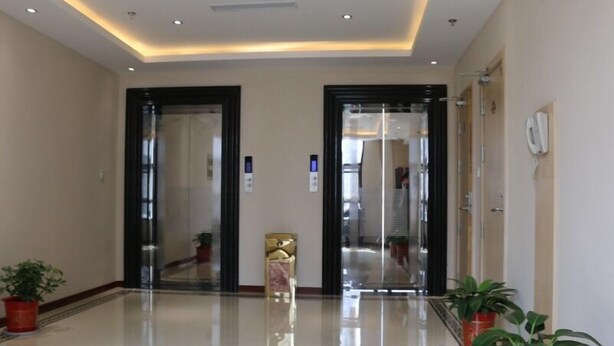 A modern hotel lobby with a polished floor, two glass doors, and potted plants. - GreenTree Alliance Suzhou Zhangjiagang Huachang Road Bus Station Hotel (Suzhou)