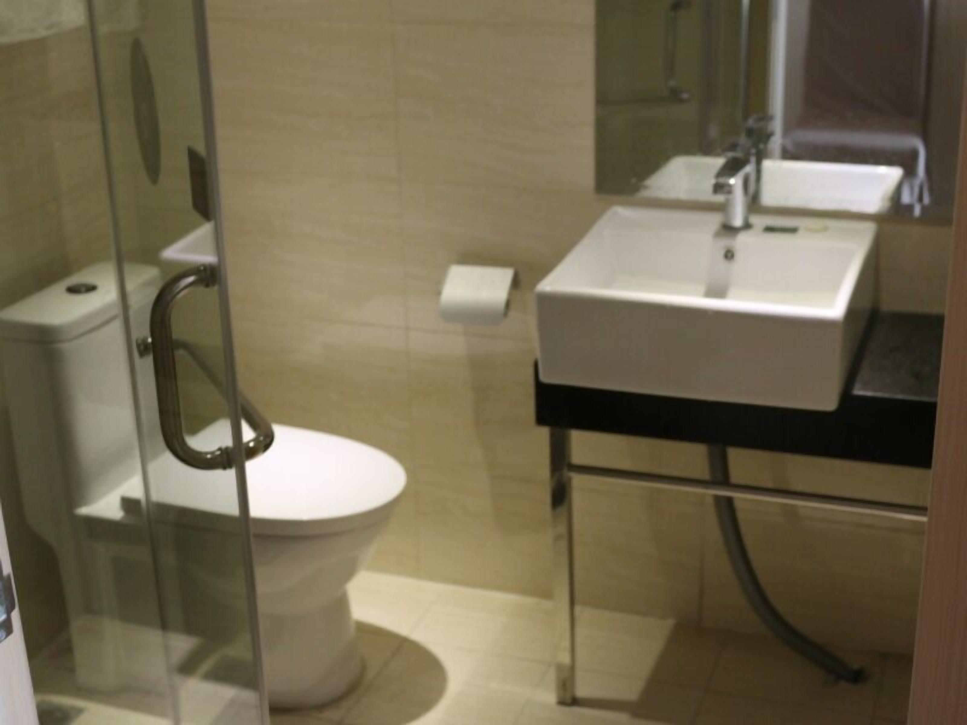 Une salle de bain avec une douche à parois de verre, des toilettes blanches et un lavabo avec un miroir au-dessus.