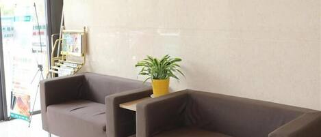 A modern lobby with two brown sofas and a potted plant.