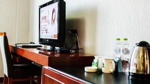 A hotel room with a wooden desk, a computer, a chair, and a coffee station with mugs and a kettle. - GreenTree Alliance Zhoushan Shenjiamen Duntou Wharf Hotel (Zhoushan)