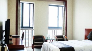 A hotel room with a bed, two armchairs, a small table, and a desk with a computer. - GreenTree Alliance Zhoushan Shenjiamen Duntou Wharf Hotel (Zhoushan)