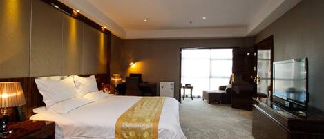 A hotel room with a large bed, a TV, a desk, and a chair.