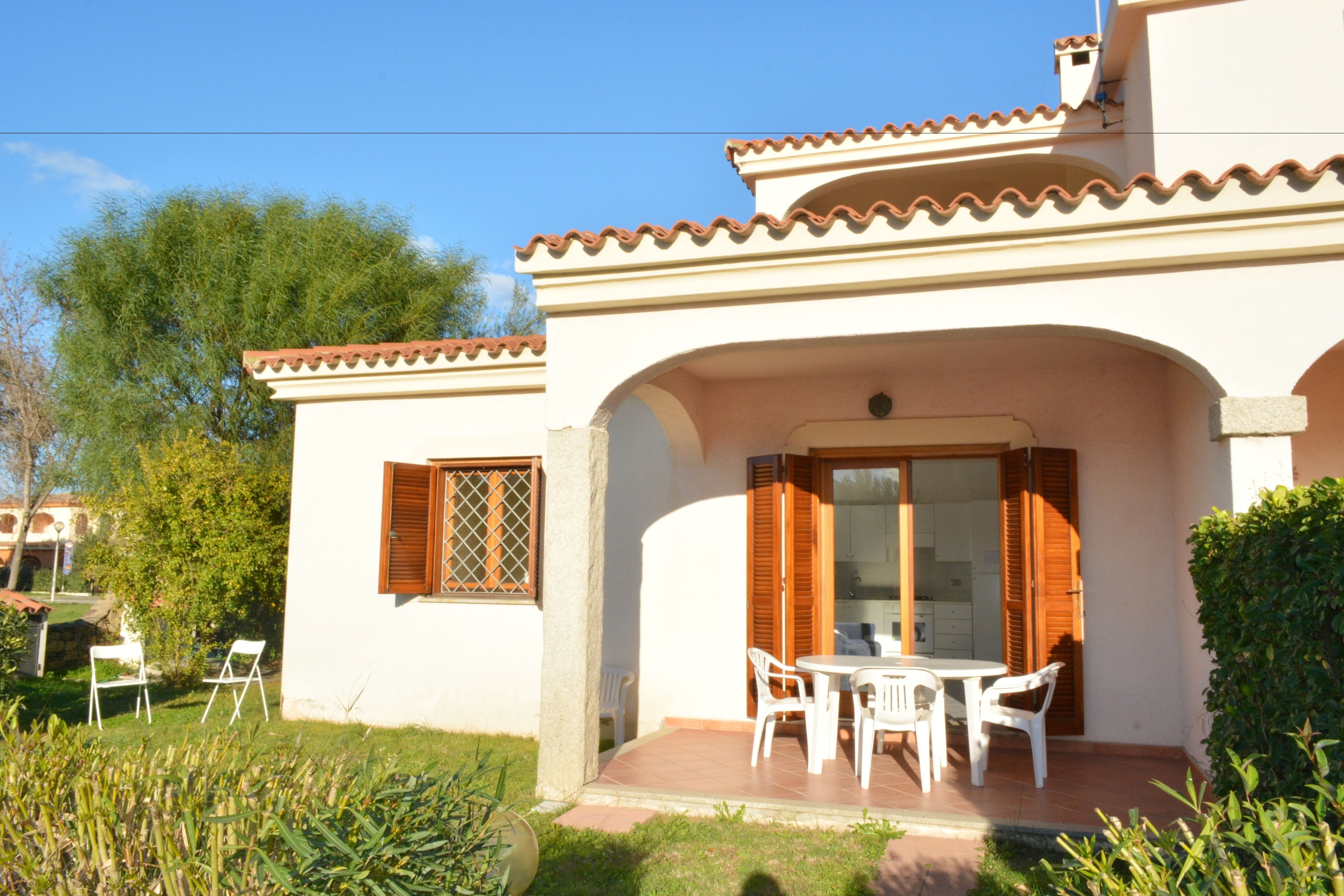 A two-story house with a patio, white walls, and a tiled roof.