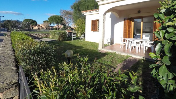 A white villa with a patio, outdoor seating, and a stone wall. - Coclearia Apartment (San Teodoro)