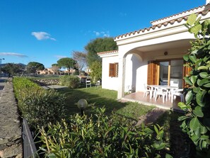 Una villa blanca con patio, mobiliario exterior y un muro de piedra.