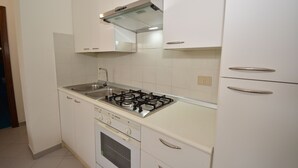 A kitchen with white cabinets, a stainless steel sink, a gas stove, and a built-in oven. - Coclearia Apartment (San Teodoro)