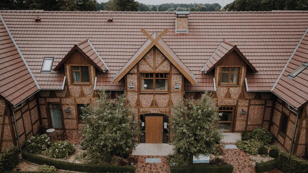 A traditional brick building with a symmetrical facade, two central doors, and a central window. - Okelmann's (Warpe)
