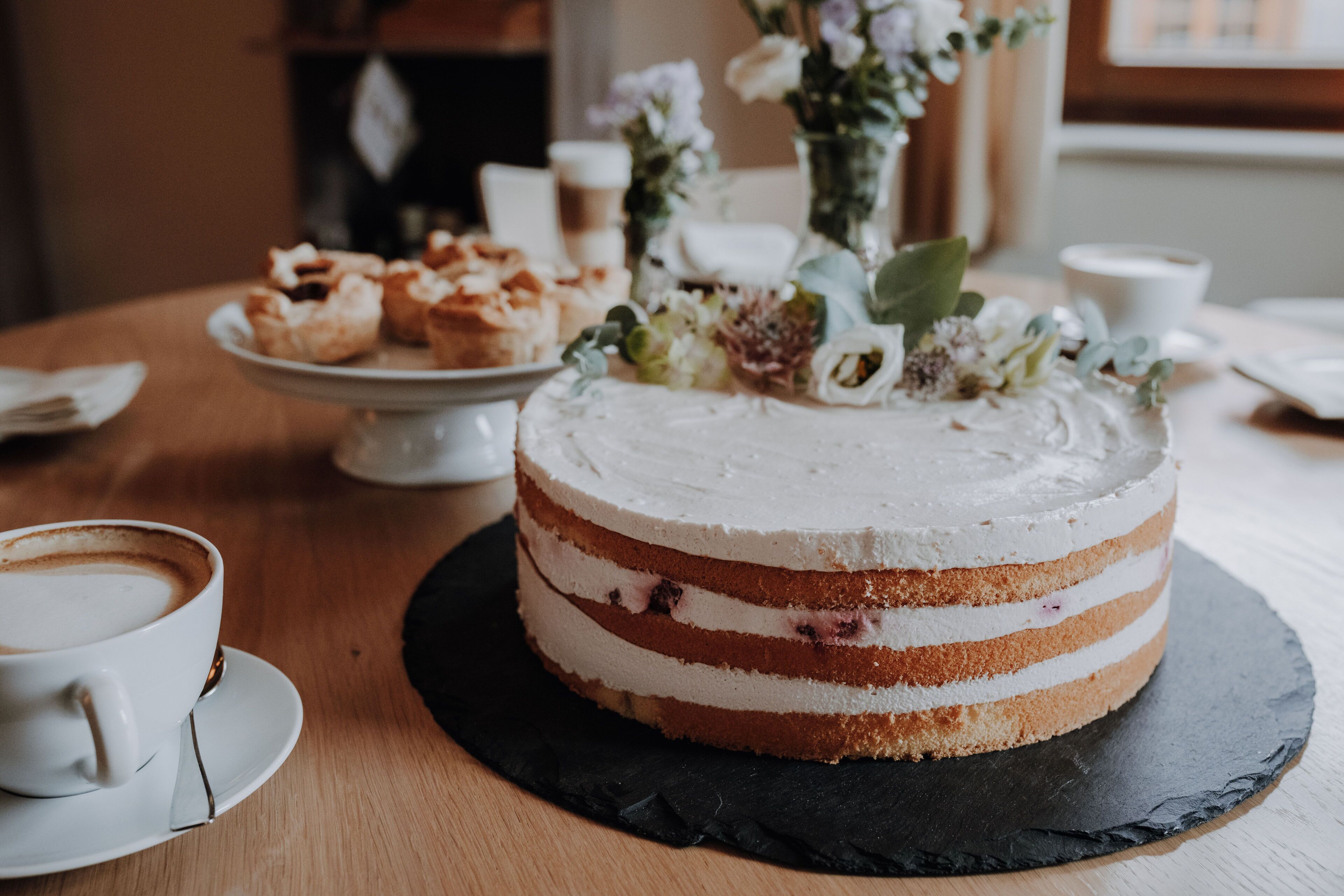 A cake with multiple layers and a cup of coffee on a wooden table.