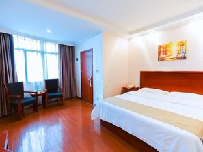 Ein Hotelzimmer mit einem Bett, zwei Stühlen, einem kleinen Tisch und einem Bild an der Wand.