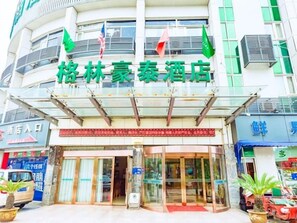 Ein Hotel mit Glasfassade, rotem Markisenvorbau und Flaggen.