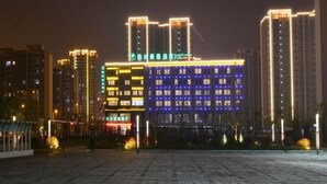 Un hotel con varios edificios altos al fondo, con señalización iluminada y una fachada bien iluminada.