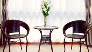 A room with two wicker chairs and a small round table with a vase of white flowers. - GreenTree Inn Nantong BaiDian Town XiuShuiYuan Express Hotel (Nantong)