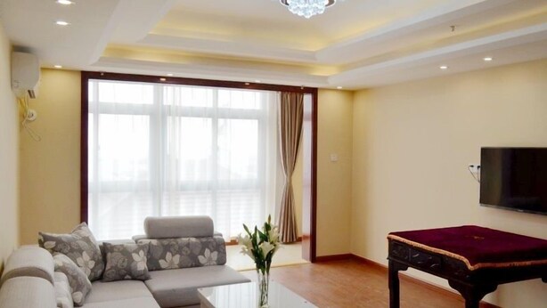 A living room with a sofa, a coffee table, a TV, and a pool table. - GreenTree Inn Nantong BaiDian Town XiuShuiYuan Express Hotel (Nantong)