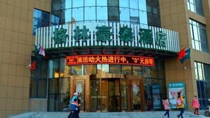 Un hôtel doté d’une façade moderne en verre et d’une enseigne en caractères chinois.