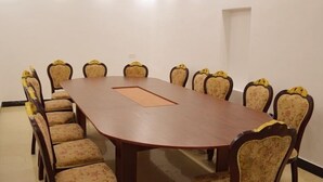 Un salón de conferencias con una larga mesa rectangular y ocho sillas con tapicería floral.