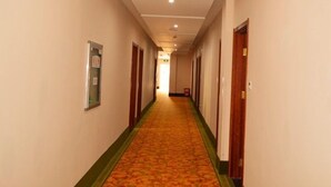 Un pasillo de hotel con pisos alfombrados, puertas de madera y paredes de color claro.