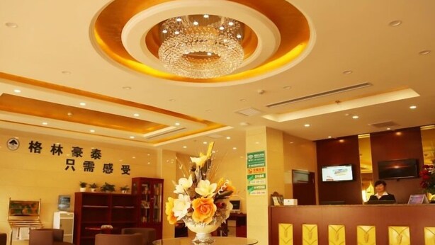 A hotel reception area with a chandelier, reception desk, and a vase with flowers. - GreenTree Inn HanZhong Railway Station BeiYiHuan Road Express Hotel (Hanzhong)