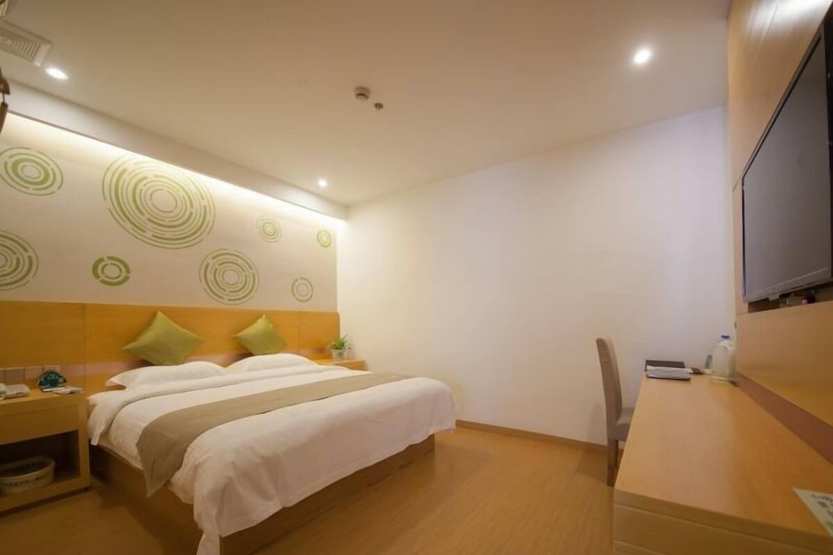 Ein Hotelzimmer mit einem Bett, Nachttischen, einem Schreibtisch und einem Fernseher.