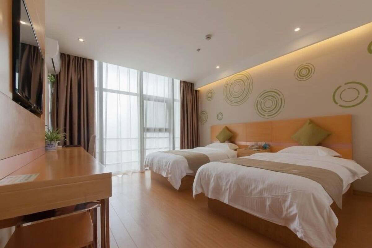 Ein Hotelzimmer mit zwei Betten, einem Schreibtisch und einem großen Fenster.