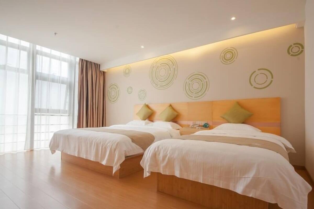 Ein Hotelzimmer mit zwei Betten, einem großen Fenster mit Vorhängen und einer Wand mit kreisförmigem Muster.