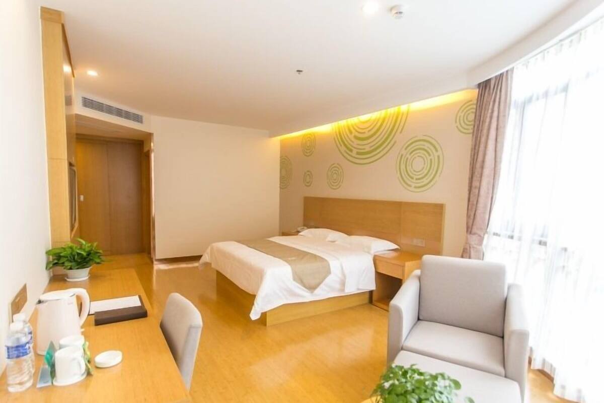 Une chambre d’hôtel avec un lit, un bureau doté d’une machine à café, une chaise et une plante en pot.