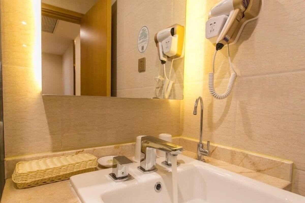Une salle de bain équipée d’un lavabo, d’un miroir, d’un sèche-cheveux et d’un porte-serviettes.