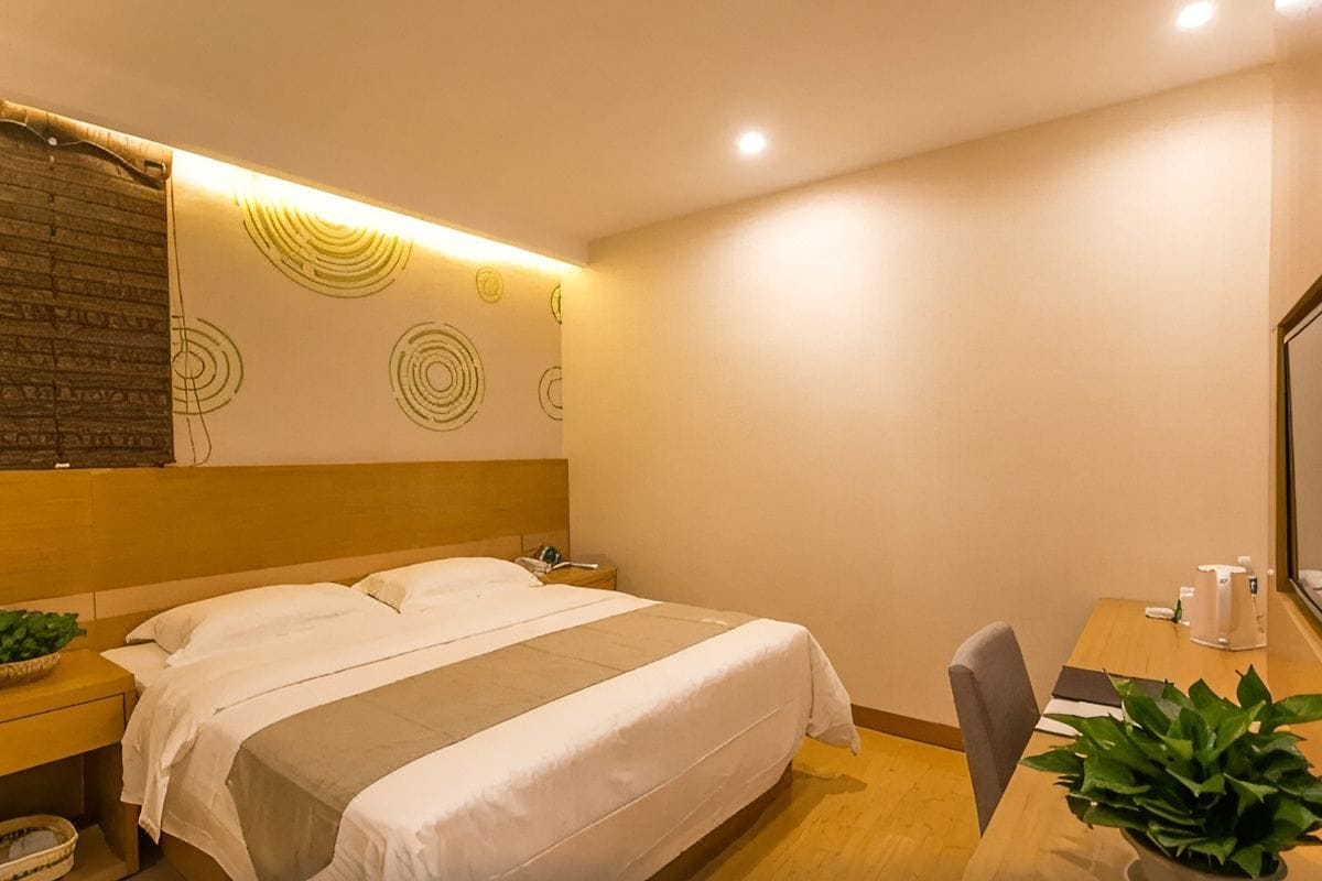 A hotel room with a bed, bedside tables, a desk with a chair, and a large mirror.