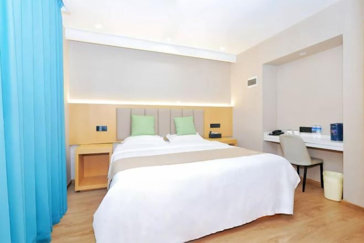 A hotel room with a large bed, a desk, and a chair.