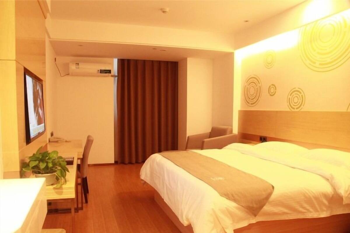 Ein Hotelzimmer mit Bett, Schreibtisch, Stuhl und einer Topfpflanze.
