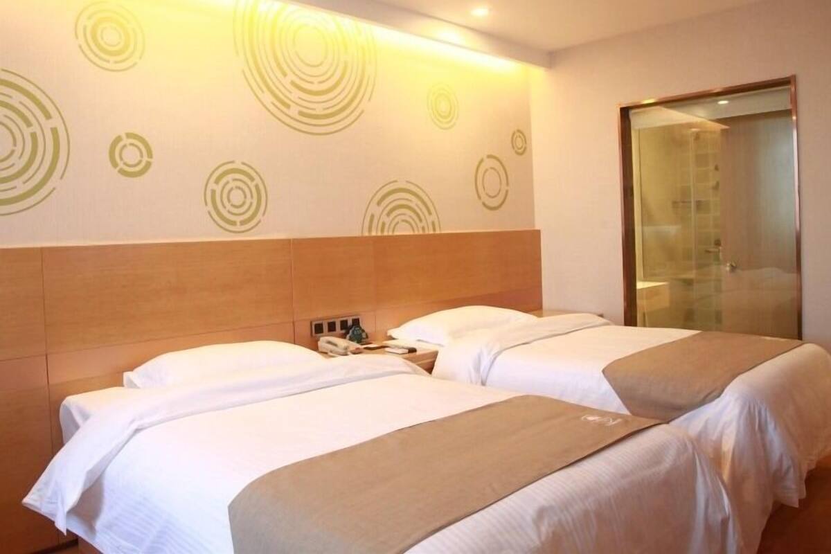Ein Hotelzimmer mit zwei Betten, einem hölzernen Kopfteil und einer Wand mit kreisförmigen Mustern.