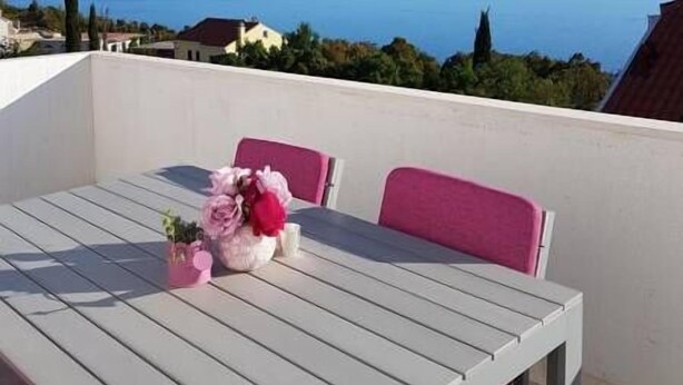 Un balcón con mesa y sillas, con vistas al mar.