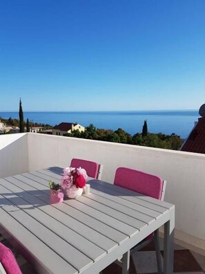 Ein Balkon mit Tisch und Stühlen mit Blick auf die Küste.