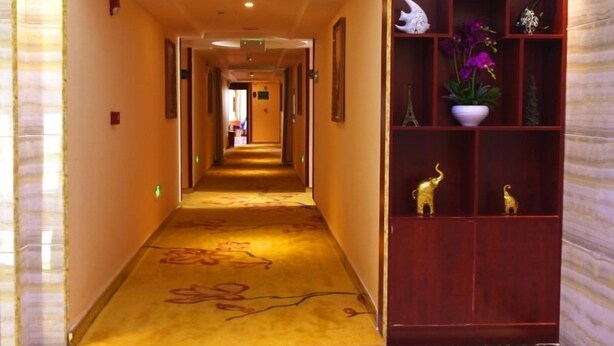 A hotel hallway with a carpeted floor, a wooden reception desk with decorative items, and a sign indicating room 7F. - GreenTree Alliance Shenzhen Fuyong Metro Station Hotel (Shenzhen)