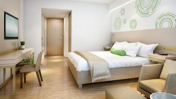 Una camera d'albergo moderna con un letto, una scrivania e una sedia. Si vede una porta che conduce in un'altra stanza.
